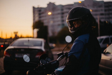 A female motorcyclist riding a motorcycle in the city in the evening