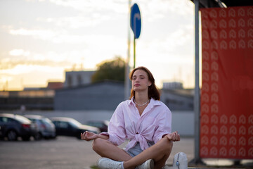 woman meditates on a bench on a city street, a concept of professional burnout and harmony.