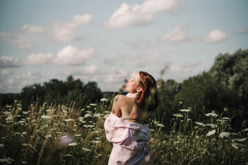 A woman walks through a field of tall grass in summer