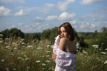 A woman walks through a field of tall grass in summer