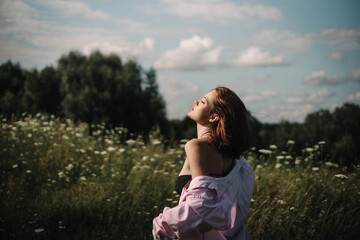A woman walks through a field of tall grass in summer