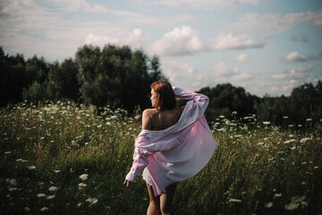 A woman walks through a field of tall grass in summer