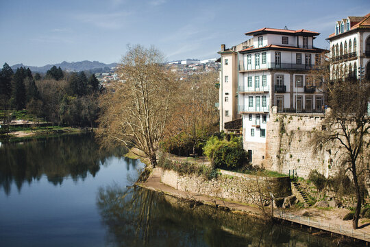 Riverside view of Amarante, Portugal, with traditional houses perched above the Tamega River and reflections in calm water.