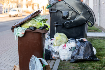 Big plastik overloaded dumpster bin container full plastic trash litter bags at residential building german downtown or suburban area. Non-recyclable sorting garbage disposal. Garbage service strike