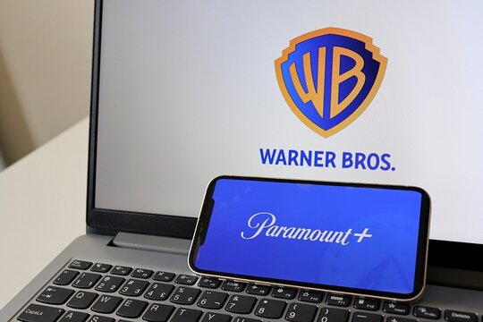 Salvador, Brazil - February 28, 2026: Paramount logo on smartphone screen with Warner Bros logo in the background. Paramount and Warner Bros. 