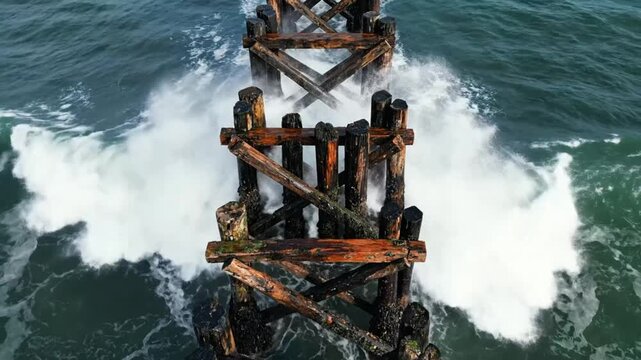 Weathered wooden pier pilings withstand ocean waves creating a dramatic waterscape