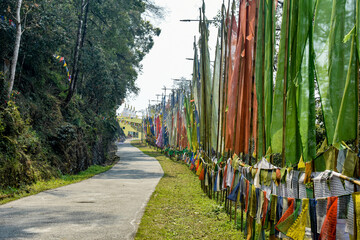 Colorful Buddhist prayer flags fluttering along mountain walkway under cloudy sky in Sikkim.