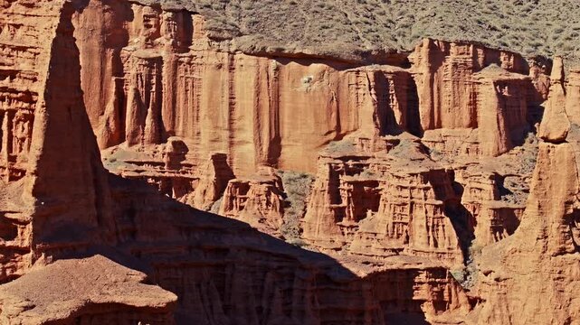 Aerial view captures stunning rock pillars amidst vast desert landscape in Kyrgyzstan. Remote canyon showcases weathered cliffs and dry terrain.