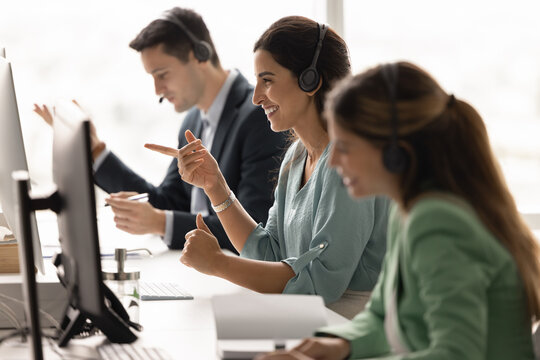 Diverse customer care team sitting at desk in headsets communicating online via computers managing client relationships handling inquiries providing professional friendly service in call centre office