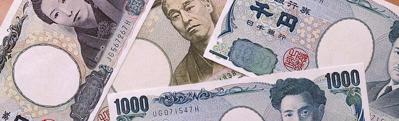 Japanese yen money bills pile on table. Japan banknotes of JPY currency close up. © Larysa