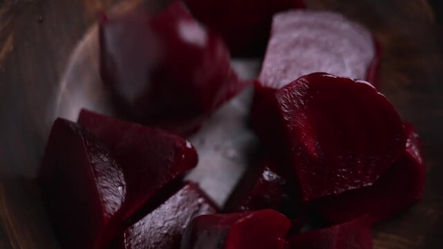 Falling slices of cooked beetroot dropping into a wooden bowl. Boiled red vegetable pieces in motion during food preparation
