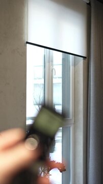 woman controls the remote control for the automatic roller shutter closing system. professional window shading salon, electric drive, servo drive, elite technologies