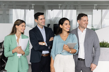 Obraz premium Diverse group of business colleagues company workforce members standing in office smiling looking aside enjoying friendly corporate culture shared goals and values positive vision for future success
