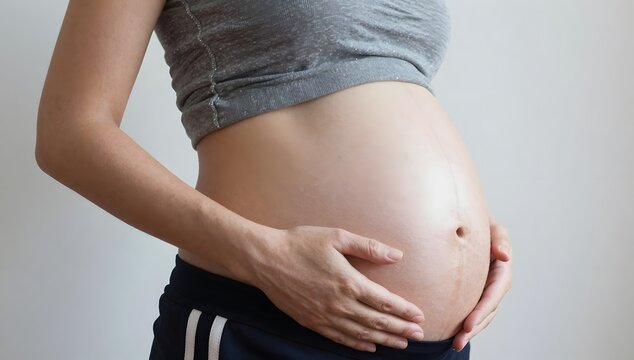 Pregnant woman's abdomen shows the round shape of the baby inside of her womb
