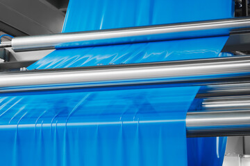 Automatic polyethylene plastic bag production machine with lighting effect. Close-up of the roller of the plastic bag production machine in the light blue scene. product packaging concept