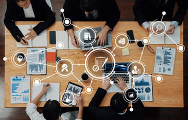 Fototapeta premium A top view of a business meeting where professionals engage in data analysis and strategic discussions around a wooden table in a modern office environment. Amity