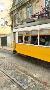 Lisbon, Portugal &ndash; January 31, 2025: Traditional Yellow Trams 28 and 12 Passing on Narrow Street