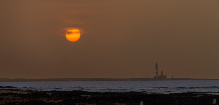 Stunningly beautiful Sunset behind the historic Faro del Toston traditional lighthouse near El Cotillo and Corralejo in Fuerteventura Canary Islands Spain