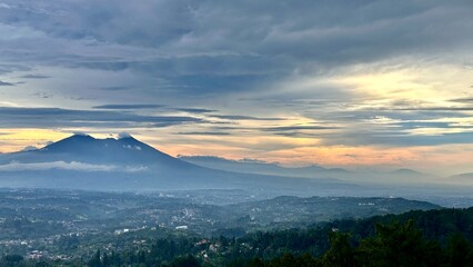 Fototapeta premium Scenic view of a vibrant sunset over a distant mountain range, featuring dramatic sky colors transitioning from deep blue to bright orange and golden yellow.
