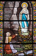 Stained glass (1916) of Apparition of the Virgin Mary, Our Lady of Lourdes to Bernadette Soubirous.