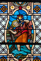 Stained glass (1916) of Saint Christopher holding the Infant Jesus on his shoulders as he crosses the river.