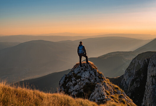 A man who enjoys hiking takes a break look at the top of the mountain at sunset adventure travel.