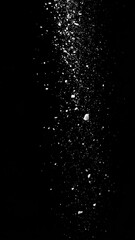 White dust, or debris falling down against a black backdrop