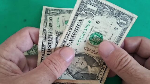 Hand holding stack of US one dollar bills closely
