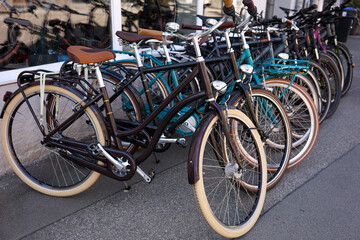 Row of classic style bicycles displayed outside an urban storefront. 