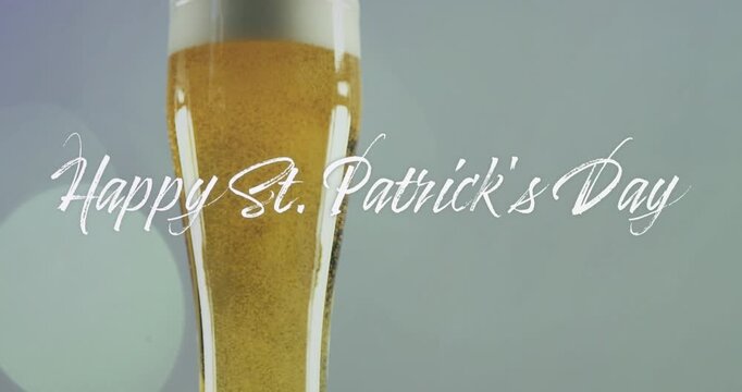 Pouring filling tall pilsner glass, golden beer rising foam, Happy St Patrick's Day text obscuring