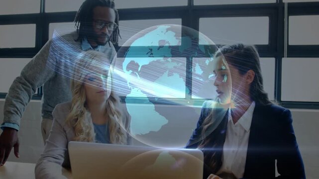 Globe appearing over laptop causing hologram data display, technology team leaning in and analyzing