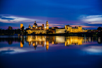 Fototapeta premium Panoramic evening view of Mantua, Lombardy, Italy; scenic twilight skyline view of the medieval town reflected in the lake waters