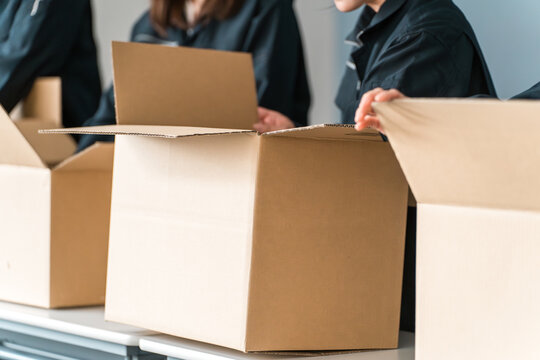 A worker from a transportation, logistics, courier, distribution, delivery, or delivery company packing items into cardboard boxes