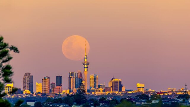 the moon rises over city skyline at sunset