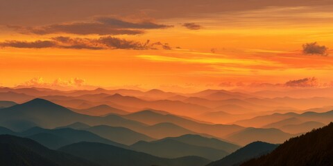 Breathtaking Sunrise Over Mountain Range with Vibrant Orange and Yellow Sky Reflecting on Rolling Hills and Layers of Distant Peaks