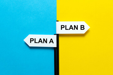 A mage of two white arrow signs labeled PLAN A and PLAN B pointing in opposite directions on a...