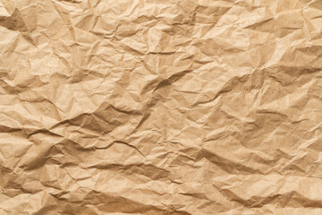Fototapeta premium A crumpled and flattened brown craft paper sheet, showcasing a dense network of creases, ridges, and organic textures that create a dynamic play of light and shadow.