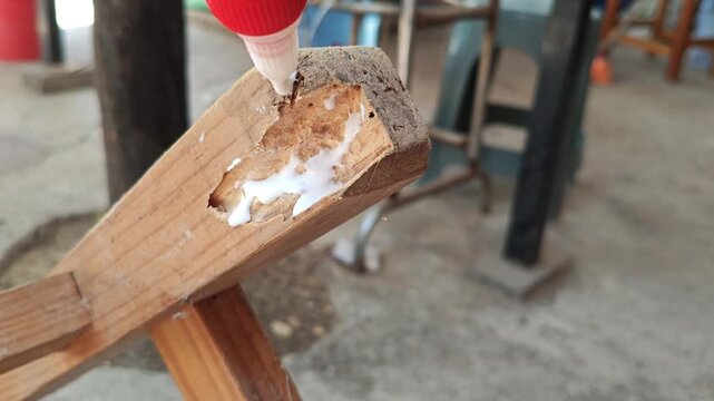 Applying white glue to a damaged wooden chair leg