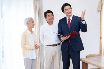 高齢夫婦に説明するスーツ姿の営業マン｜介護・保険・住宅相談