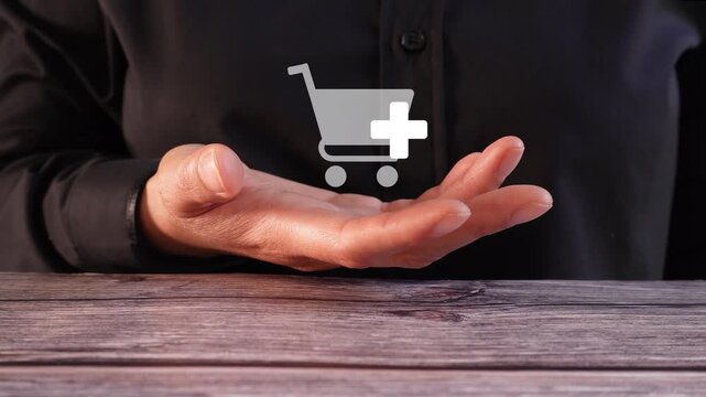 Close-up of a woman's hand on a table holding an animated shopping icon with the add-on button. Add more products to your cart.
