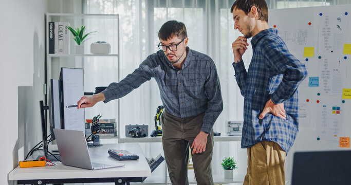 Team adult male engineer collaborate on robotic hand project using AI code solutions machine learning at tech workspace. Artificial intelligence interface, collaboration support prototype development.