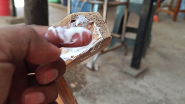 Applying white wood glue with finger on furniture base