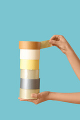 Female hands with adhesive tape rolls on blue background