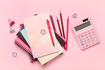 Obraz premium Stack of different notebooks with stationery and calculator on pink background