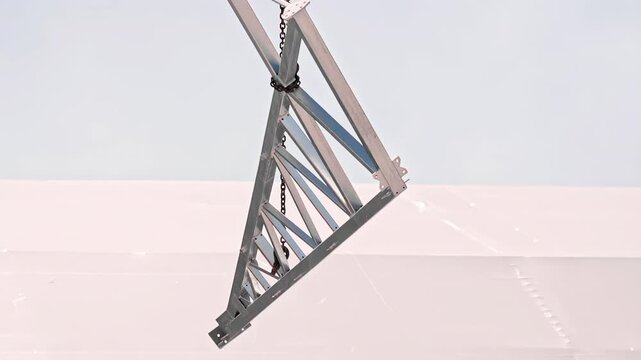 Steel truss structure being lifted by crane during industrial installation on rooftop construction site