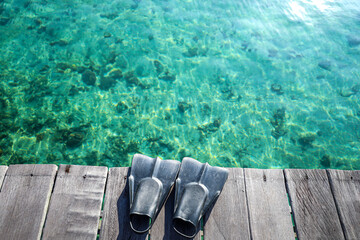 Tropical Scene with Snorkel Fins on a Wooden Pier Over Clear Water © LiamProject