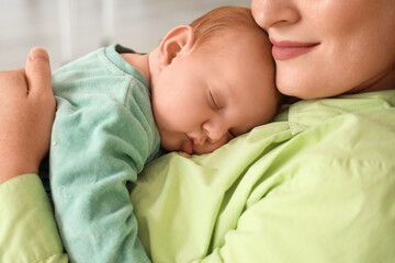 Beautiful young mother with her cute little sleeping baby sitting on rocking chair at home, closeup