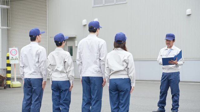工場の前でミーティングする作業員グループ
