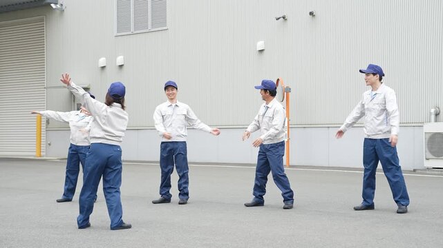 工場の前で体操する作業員グループ