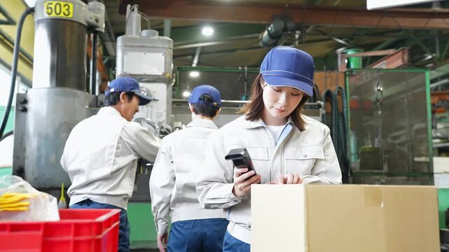 工場でハンディターミナルを使って製品を検査する女性作業員